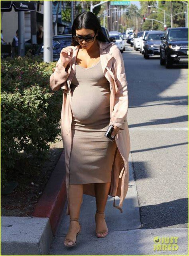 A pregnant Kendall Rae (right) coddling her dog leaping on her lap as her husband Josh Thomas (left) touched her belly for a romantic pose.