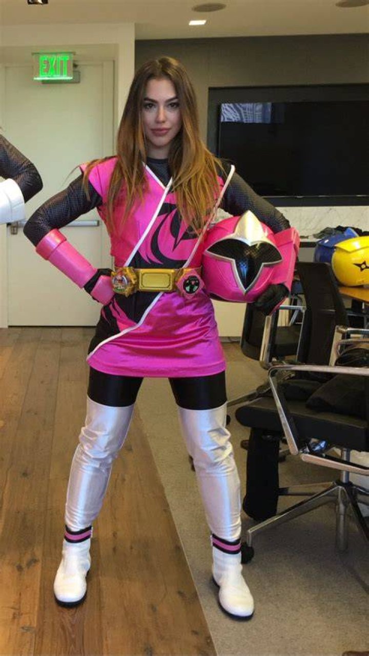 Chrysti Ane wearing long black jacket and black high boots carrying pink hand bag