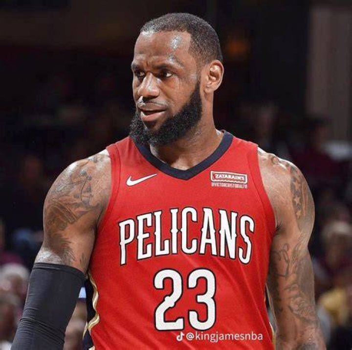He is wearing a Pelicans cap and sitting on the stands with a smile on his face.