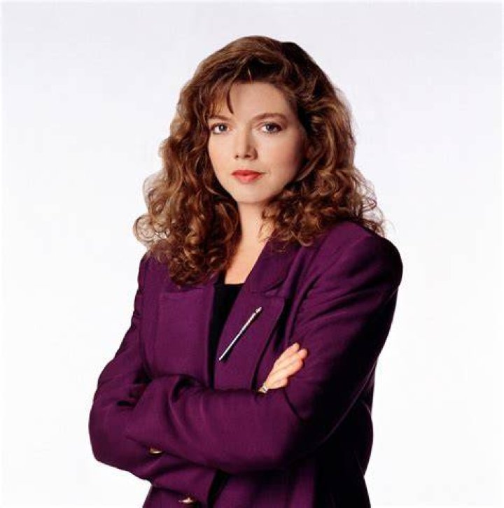 Picture of Catherine Disher pointing her finger to the camera wearing red dress and white necklace